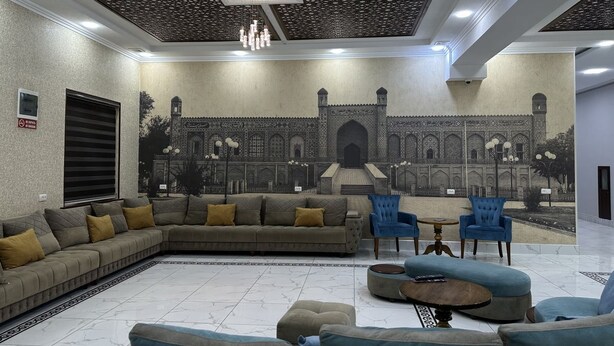 A spacious living area with a large sofa, blue armchairs, and a coffee table. - Reikartz Grand Kokand (Kokand)