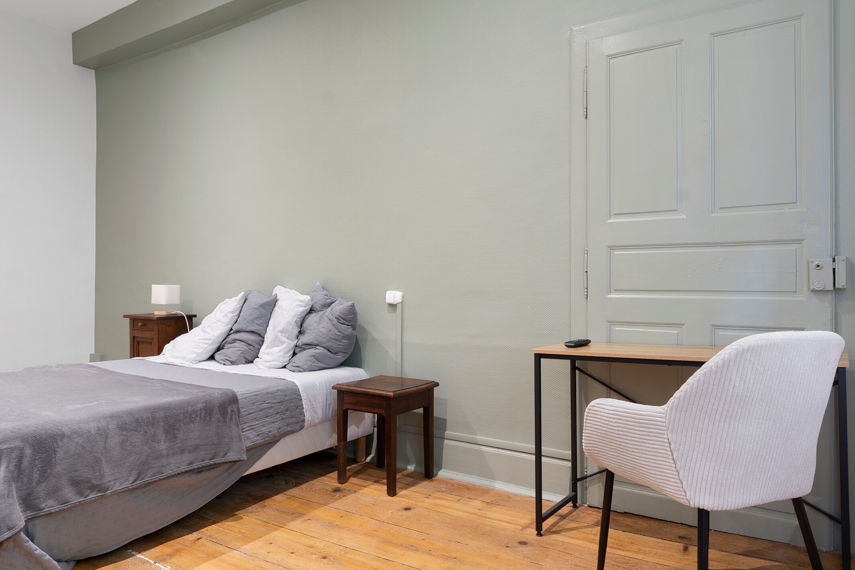 Une chambre à coucher avec un lit, une table de chevet, une chaise et une porte.