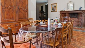 Un coin repas comprenant une table ronde, des chaises, un buffet en bois et une cheminée.
