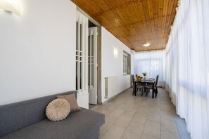 A modern interior with a grey sofa, wooden ceiling, and a dining area with a table and chairs. - The apartment is modern, well-organized, and designed to provide comfort and functionality throughout your stay. The spaces are bright and spacious, with a layout that can comfortably accommodate up to six people.It features three bedrooms: two double be (Lido di Camaiore)