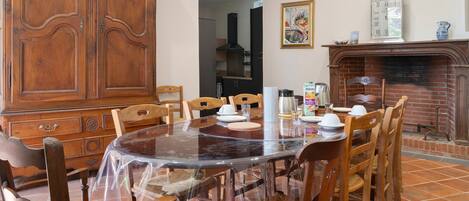 Un coin repas comprenant une table ronde, des chaises, un buffet en bois et une cheminée.