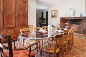 A dining area with a round table, chairs, a wooden cabinet, and a fireplace.