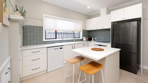 Una cocina moderna con armarios blancos, un refrigerador negro y una ventana con vistas al exterior.