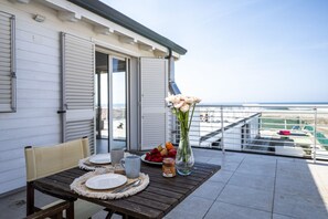 A dining table set on a balcony with a view of the sea, a vase with flowers, and a plate of fruit. - The apartment is modern, well-organized, and designed to offer comfort and functionality throughout your stay. The spaces are bright and airy, with a layout that allows for easy movement even with multiple guests.It features two bedrooms: one with a doub (Lido di Camaiore)