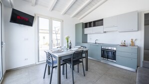 Uma cozinha moderna com forno embutido, uma mesa de jantar com cadeiras e uma TV na parede exibindo o logotipo da Netflix.