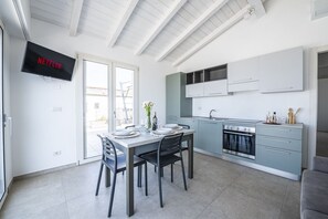 A modern kitchen with a built-in oven, a dining table with chairs, and a TV mounted on the wall displaying the Netflix logo. - The apartment is modern, well-organized, and designed to offer comfort and functionality throughout your stay. The spaces are bright and airy, with a layout that allows for easy movement even with multiple guests.It features two bedrooms: one with a doub (Lido di Camaiore)