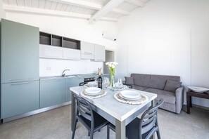 A modern kitchen with light blue cabinets, a dining table set with plates and glasses, and a gray sofa in the living area. - The apartment is modern, well-organized, and designed to offer comfort and functionality throughout your stay. The spaces are bright and airy, with a layout that allows for easy movement even with multiple guests.It features two bedrooms: one with a doub (Lido di Camaiore)