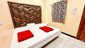 A hotel room with a bed, a headboard, a wall-mounted curtain, and a light switch. - Hotel S C PALACE near Mahakal Temple (Ujjain)