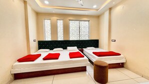 A bedroom with two beds, a large window, and a ceiling light. - Hotel S C PALACE near Mahakal Temple (Ujjain)
