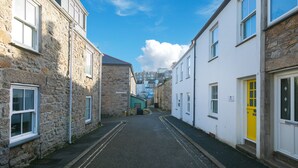 A narrow street with stone and white buildings, a yellow door, and a clear blue sky. - Dan’s Den, St Ives– Sleeps 4 – Dog Friendly – Wood Burner (St Ives)