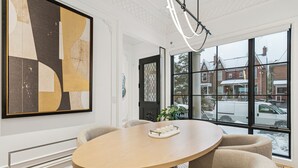 Ein moderner Essbereich mit einem runden Tisch, beigen Stühlen und einem großen abstrakten Gemälde an der Wand.