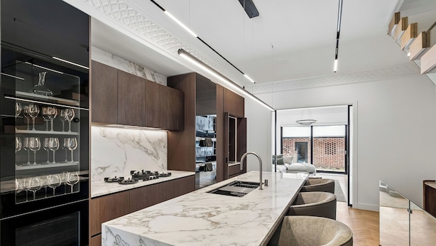 Eine moderne Küche mit Marmorarbeitsplatte, integriertem Weinkühlschrank und Blick ins Freie.
