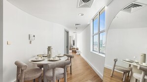 Een moderne eetruimte met een ronde tafel voor vier personen, een krabpaal en een uitzicht op de stad door grote ramen.