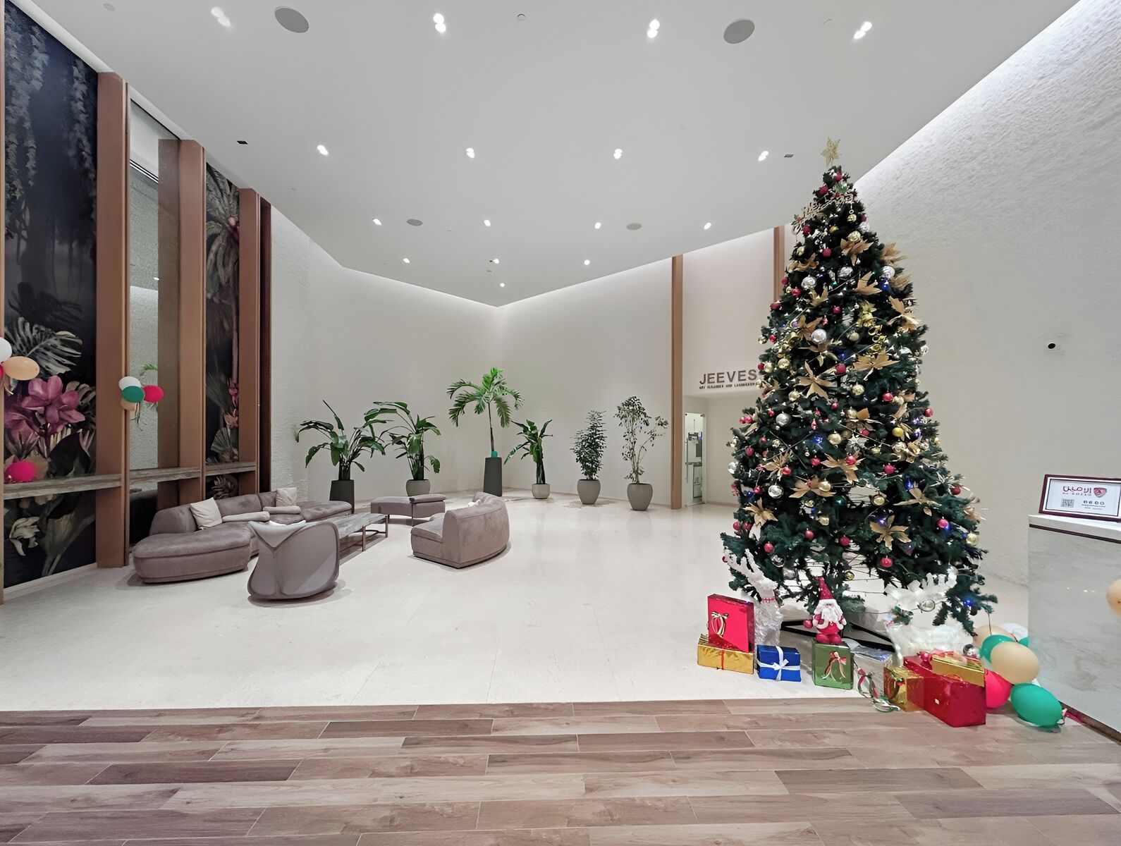 Een moderne lobby met een grote kerstboom, een zithoek en potplanten.