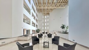 Een ruime lobby met hoge plafonds, meerdere verdiepingen en modern meubilair.