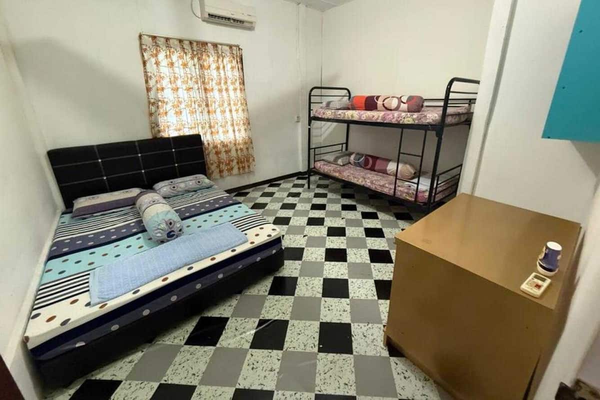 A dormitory room with a single bed, bunk beds, a checkered floor, and a small table with a scale.