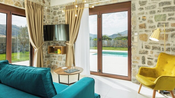 Una sala de estar moderna con un ventanal grande, un televisor de pantalla plana, un sillón amarillo y un sofá color turquesa.