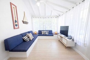 A modern living room with a sofa, TV, and a ceiling fan. - Complete house in Búzios with pool and gourmet area for up to 10 people. (Armação dos Búzios)