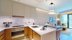 Cozinha moderna com forno embutido, pia e torradeira. Possui área de jantar com mesa e cadeiras.