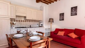 Una cucina con mobili bianchi, un divano rosso e due opere d'arte a parete.