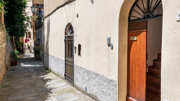 Un vialetto stretto con un edificio che presenta una porta in legno e un cancello in metallo.