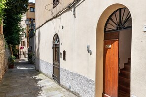 A narrow alleyway with a building featuring a wooden door and a metal gate. - Apartment 'Vicolo del Corso - Torre' with Shared Terrace and Wi-Fi (Massa Marittima)