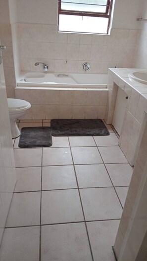 Um banheiro pequeno com azulejos, banheira, vaso sanitário e janela.