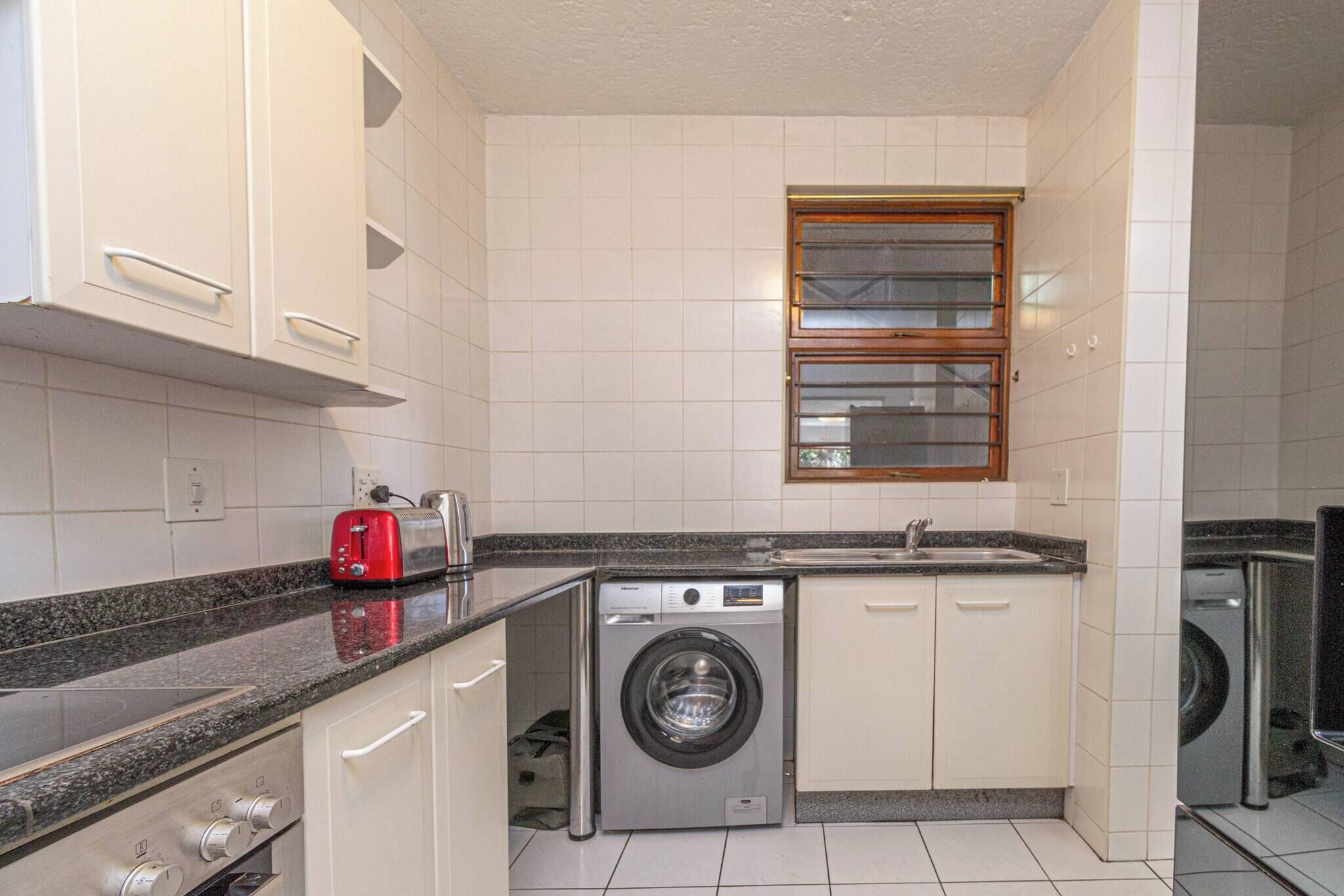 A compact kitchen with a washing machine, a toaster, and a sink.