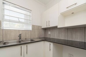 Eine Küche mit weißen Schränken, einer doppelten Spüle und einem Fenster mit Jalousien.