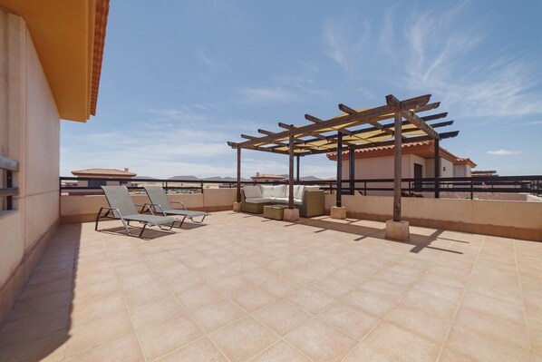A rooftop terrace with a pergola, lounge chairs, and a sofa.
