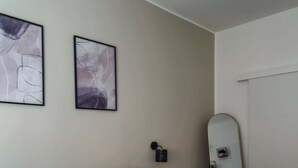 A hotel room with a bed, pillows, a bedside table, a mirror, and a folded towel on the bed. - Marsala Suites (Bologna)