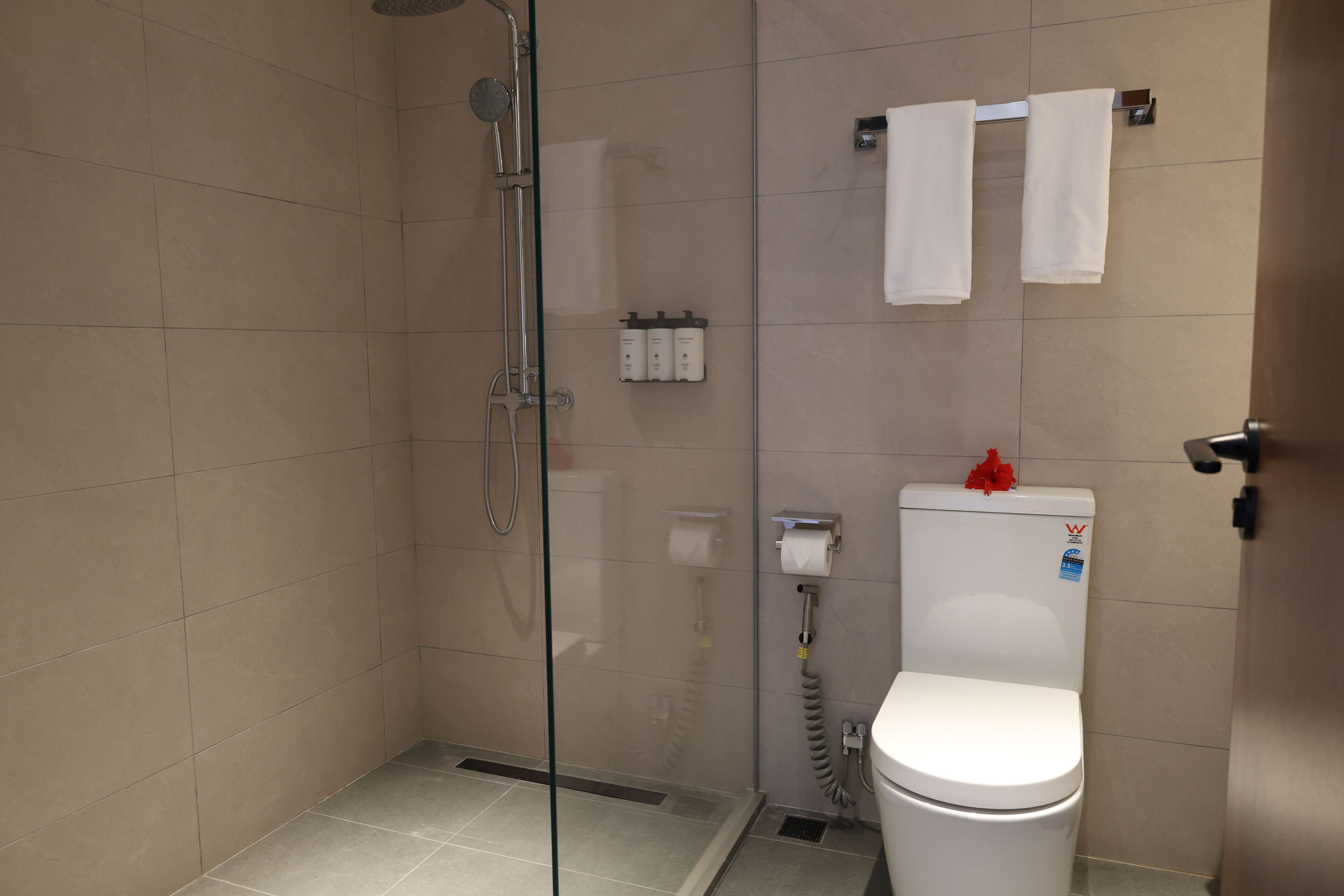 Ein modernes Badezimmer mit einer gläsernen Duschkabine, einer Toilette und einem Handtuchhalter.