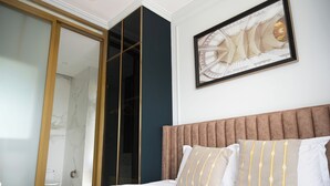 A bedroom with a bed, a large mirror, a framed artwork, and a sliding door.