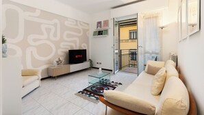 A modern living room with a sofa, TV, glass coffee table, and patterned rug. - Large Apartment Sesto Rondò M1 - Duomo 20 min (Sesto San Giovanni)