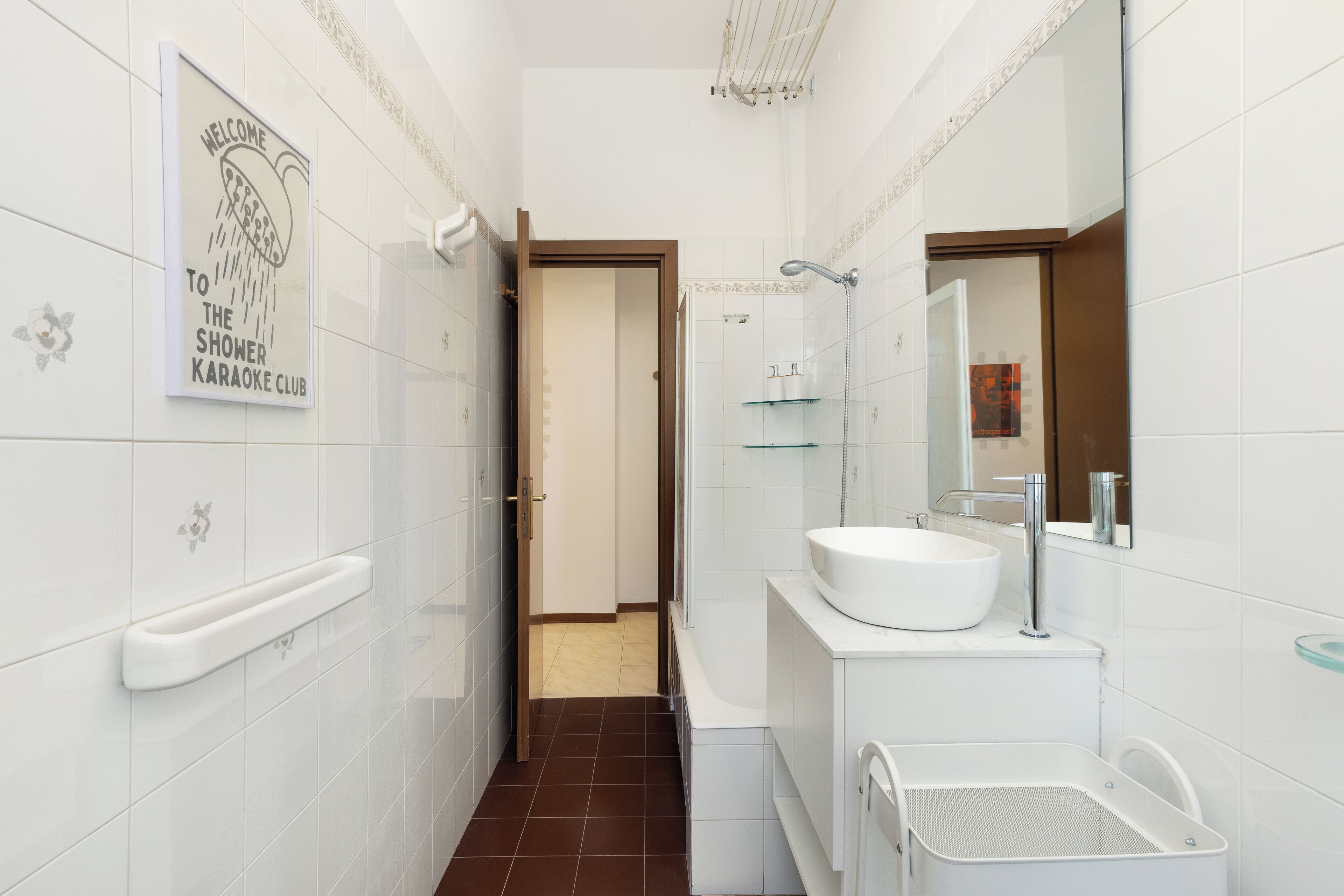 Une salle de bain moderne avec des carreaux blancs, un grand lavabo, un miroir et un espace douche.