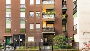 A multi-story brick building with balconies, a green door, and a gated entrance. - Large Apartment Sesto Rondò M1 - Duomo 20 min (Sesto San Giovanni)