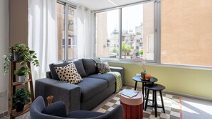 A modern living room with a grey sofa, a small round table, and a potted plant. - Cloudwalk 1- BR Apartment in Larnaca (Larnaca)