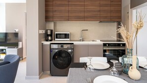 A modern kitchen with wooden cabinets, a washing machine, a microwave, and a sink. - Cloudwalk 1- BR Apartment in Larnaca (Larnaca)