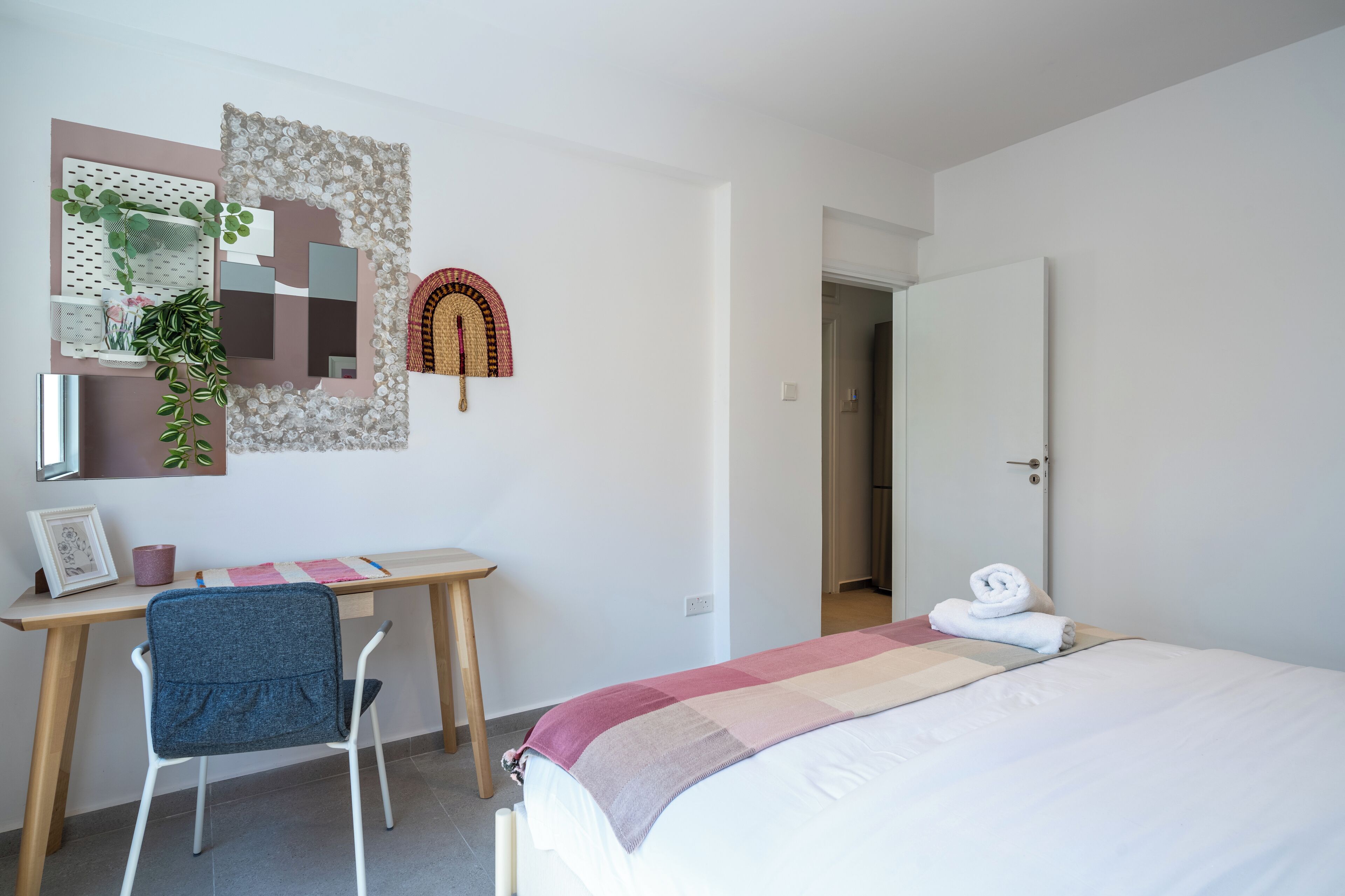 Una camera da letto con un letto, una scrivania, una sedia e una parete decorata.