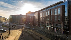 Eine moderne Stadtstraße mit Gebäuden, einer Straßenbahnhaltestelle und einem belebten Kreuzungsbereich.