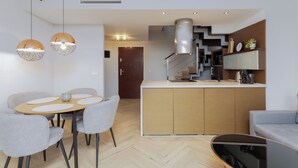 Una cocina moderna con una isla central, sillas grises e iluminación colgante.