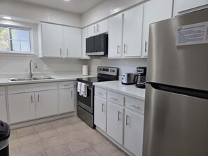 Una cocina moderna con armarios blancos, electrodomésticos de acero inoxidable y una ventana que proporciona luz natural.