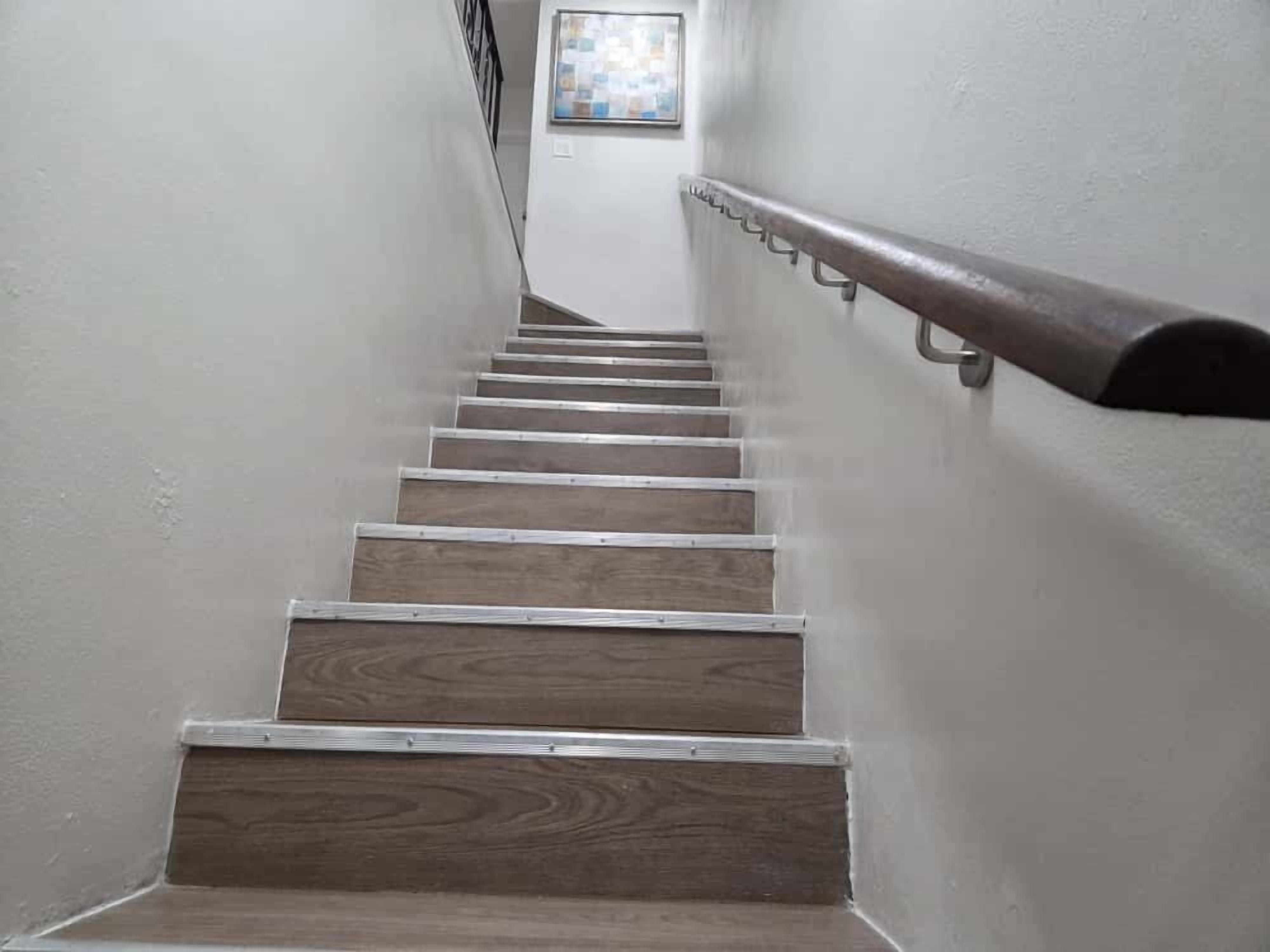 Un escalier avec des marches en bois et des rampes en métal, menant à l’étage supérieur.