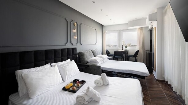 A hotel room with two beds, a dining area, and a view of the city. - King George palace (Jerusalem)