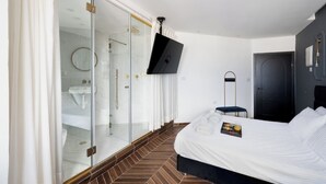 A modern hotel room with a large bed, a TV mounted on the wall, a walk-in closet, and a shower area. - King George palace (Jerusalem)