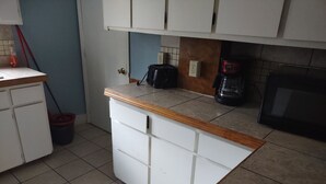 A kitchen with white cabinets, a wooden countertop, a coffee maker, and a microwave.