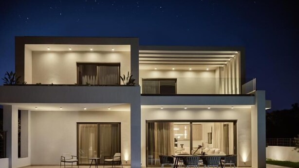 A modern two-story house with a swimming pool, outdoor seating, and a well-lit patio area. - Soleil Villas (Zakynthos)