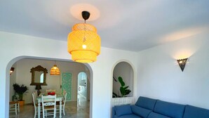 A spacious living area with a blue sofa, a dining table with chairs, and a hanging light fixture. - Patio Alcornocal by Residea (El Paraíso)