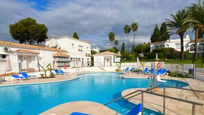 A pool area with blue lounge chairs and a clear sky. - Patio Alcornocal by Residea (El Paraíso)