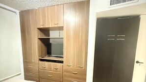 A bedroom with a bed, wooden wardrobe, and a door. - Beautiful apartment (Porlamar)